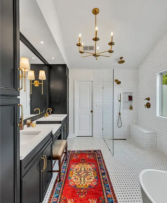 Master bathroom with black vanity, brass chandelier, hexagon floor tile and glass-enclosed shower