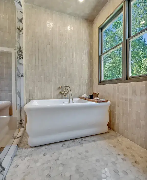 Master bath with a freestanding tub, hexagon floor tile and tall beige tile walls