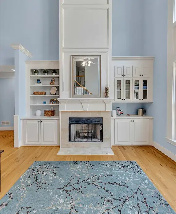 Living room with a white fireplace surround, built-in shelving and glass-front cabinets