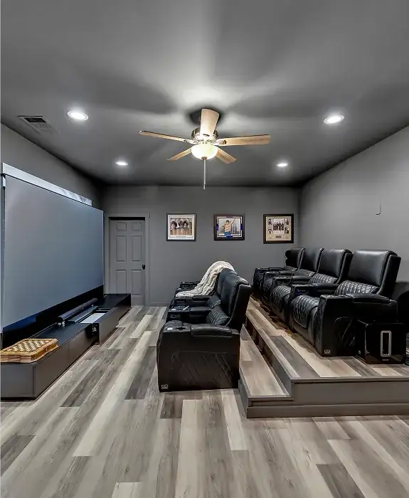 Finished basement home theater with tiered leather recliners, a large screen and gray plank flooring