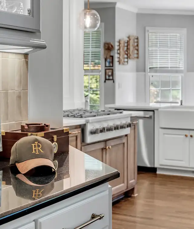 Kitchen with white cabinets, black countertop island, stainless range and farmhouse sink under a window